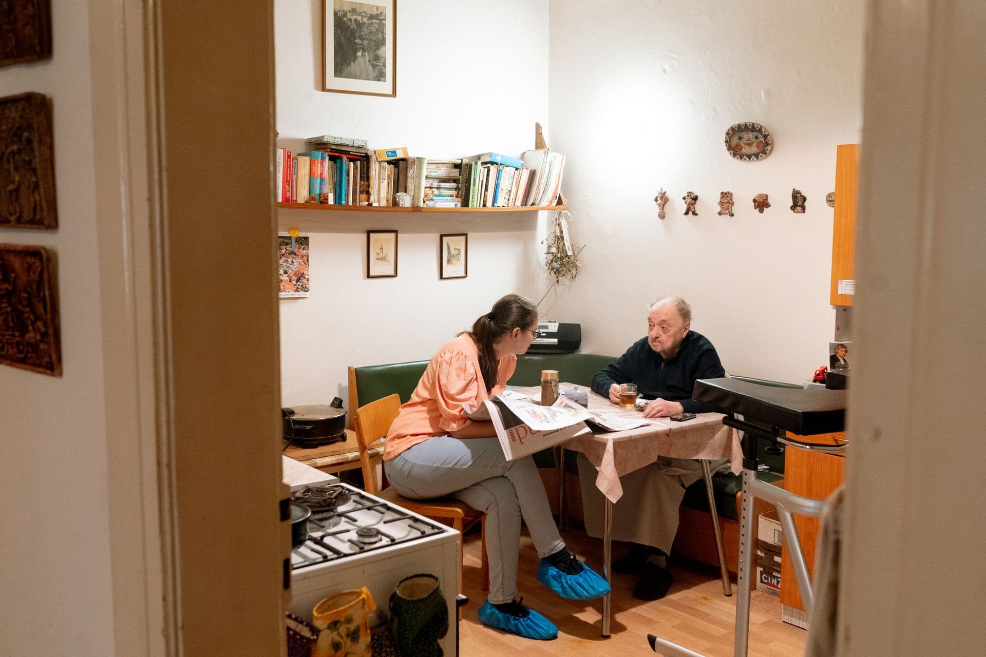 A live-in carer sharing a pot of tea with an older man in his kitchen