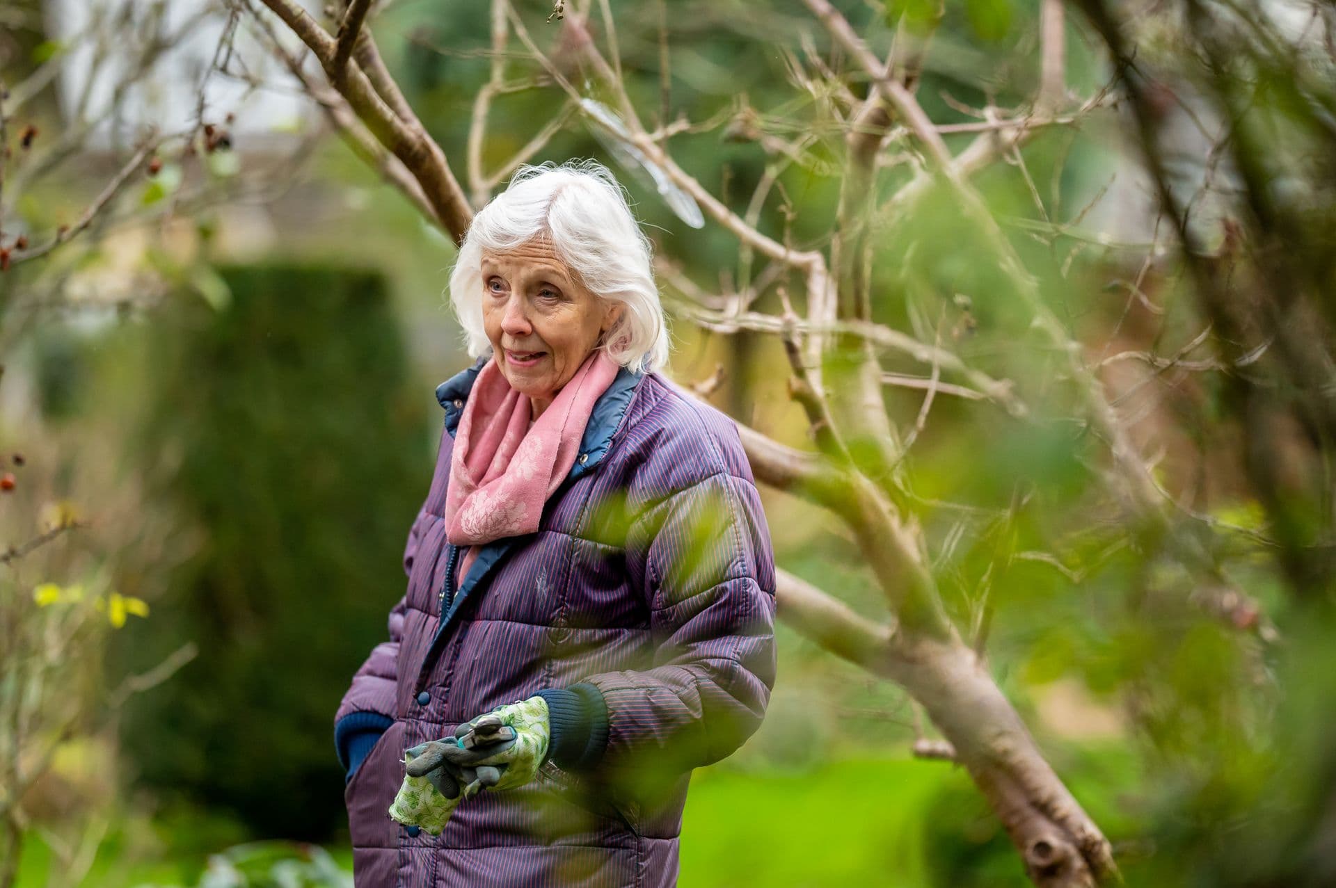 An older man enjoying his garden while a carer brings out tea