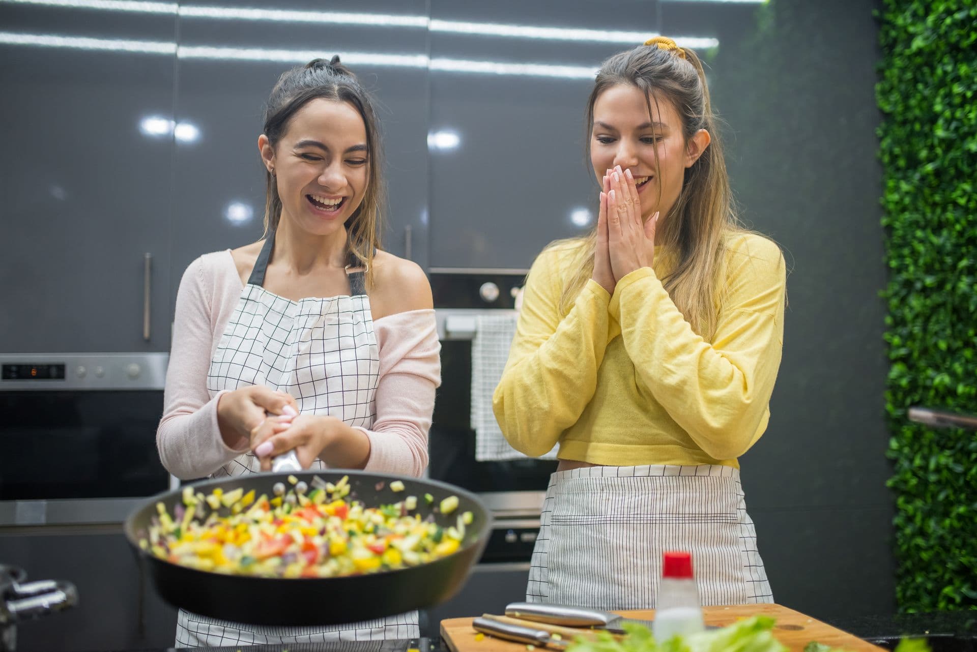 A support worker and a young adult cooking together in a bright kitchen